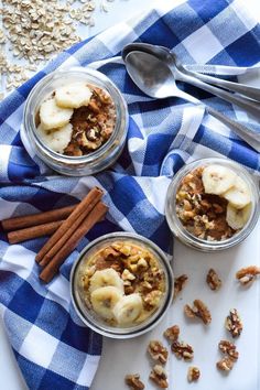 three glass jars filled with granola and bananas on top of a blue checkered towel