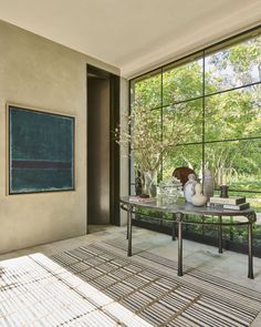 a table with vases on it in front of a large window that looks out onto the park