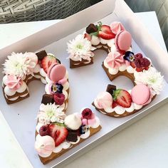 there is a cake in the shape of letter e with flowers and berries on it