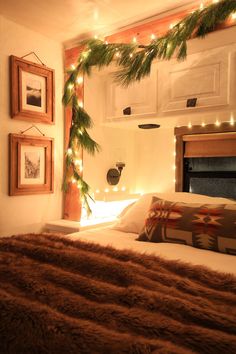 a bedroom decorated for christmas with lights on the headboard and fur throw pillow cover