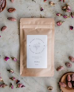 a bag of coffee sitting on top of a table next to some nuts and flowers