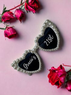 two heart shaped brooches with personalized names on them next to red roses