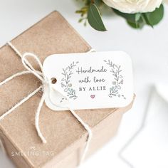 a brown box with a white tag on it next to a bouquet of flowers and greenery