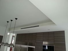 an empty kitchen with stainless steel appliances and wood paneling on the walls, along with modern lighting fixtures