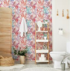 a bathroom with colorful wallpaper and a white toilet in the corner next to a wooden shelf