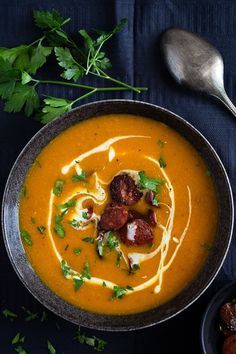 a bowl of carrot soup with meatballs and garnishes on the side