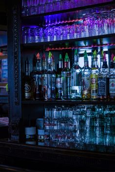 the bar is filled with many different types of liquor bottles and glasses on it's shelves