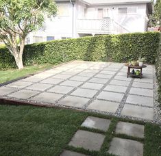 an empty patio in front of a house with green grass and plants on the side