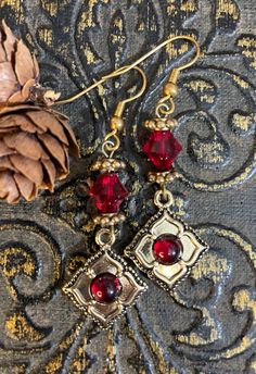 These lovely romantic red and gold vintage-style earrings are perfect for the holidays or anytime. Indie gold flower charms with red glass centers hang below bicone ruby red Swarovski crystals (which are almost impossible to find anymore). Earrings hang 2 inches from gold French ear hooks. Indie Earrings, Black Wedding Gowns, Raven Pendant, Holiday Earrings, Vintage Style Earrings, Holiday Earring, Victorian Christmas, Earrings Red, Red Earrings