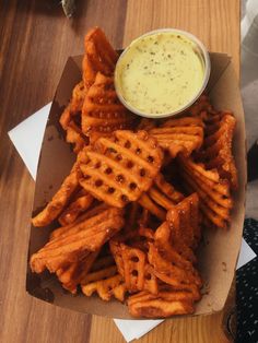 a basket filled with cheetos covered in dipping sauce on top of a wooden table