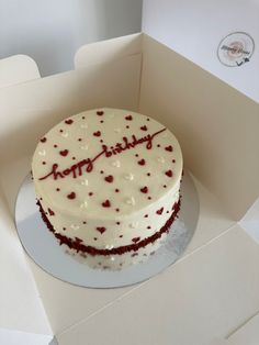 a birthday cake with white frosting and red sprinkles in a box