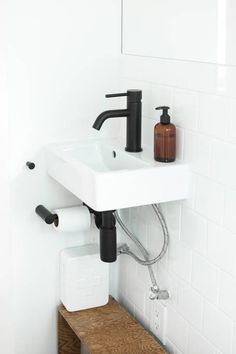 a bathroom sink sitting under a mirror next to a wooden shelf with soap dispenser