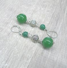 Green Jade round drop earrings with Tibetan silver beads Greenery jewelry Saint Patrick's Day gift idea healing gemstone earrings for her Length: 2.24 inches ( 57 mm ) from ear hole to the bottom. Width: 13 mm by the size of larger round beads. Drop length: 43 mm ( under 2 inches ) The drop consists of 2 round beads of green jade, measuring 6 and 13 mm in diameter. I added Tibetan silver beads, measuring 8 mm in diameter. The earrings are hung on silver plated lever back ear wires. These danglin Spiritual Round Gemstone Bead Earrings, Silver Earrings With Gemstone Round Beads, Silver Earrings With Gemstone Beads, Spiritual Hypoallergenic Round Beads Earrings, Hypoallergenic Spiritual Round Bead Earrings, Hypoallergenic Jade Silver Earrings, Jade Earrings With Gemstone Beads, Silver Gemstone Bead Round Earrings, Silver Gemstone Beads Earrings