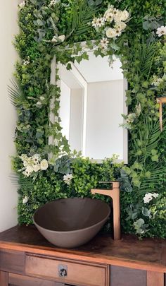 a bathroom with a mirror, sink and plants on the wall behind it that is covered in greenery