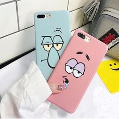 two cartoon phone cases sitting on top of a counter next to a purse and wallet