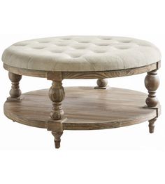 a round wooden coffee table with an upholstered cushion on it's top