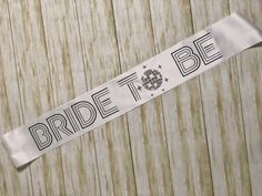 the bride to be sash is hanging on a wooden wall with wood planks behind it