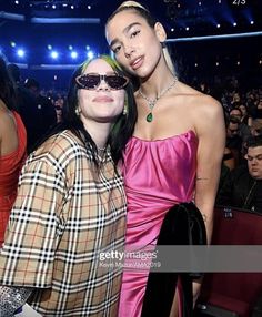 two women standing next to each other in front of an audience at a fashion show