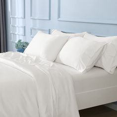 a bed with white sheets and pillows on it