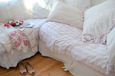 a bed with white sheets and pink flowers on it next to a pair of shoes