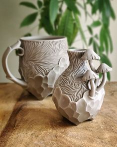 two ceramic mugs sitting on top of a wooden table