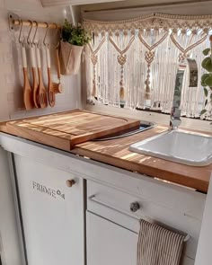 a kitchen counter with cutting boards on it and utensils hanging from the wall