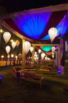 lanterns are lit up in the night sky at an outdoor wedding venue with purple and blue lighting