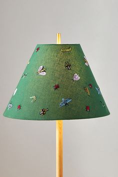 a green lampshade with various stickers on it and a yellow wooden base