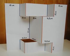 an open box with measurements on it sitting on top of a white table next to a wood paneled wall