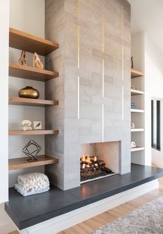 a modern fireplace in a living room with shelves on either side and a fire place at the end