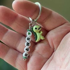 a hand holding a key chain with a green frog on it