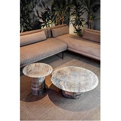 two tables sitting next to each other in front of a couch and table with plants on it