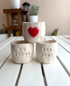 three ceramic bowls sitting on top of a white table next to a potted plant