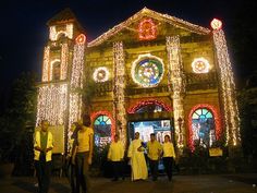 people are standing in front of a church decorated with christmas lights