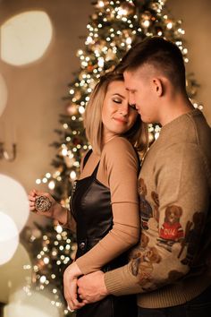 a man and woman standing in front of a christmas tree