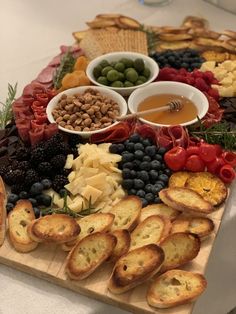 a platter with bread, olives, tomatoes, grapes and other food items