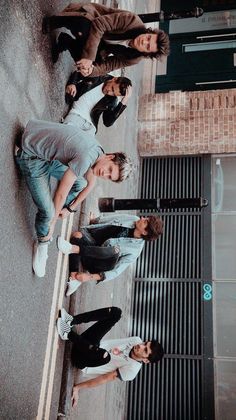 four young men are standing on the side walk