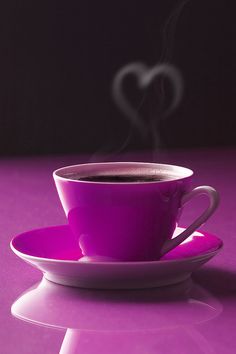 a purple coffee cup and saucer with steam rising out of it on a pink table