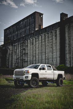 a white truck parked in front of a large grain silo