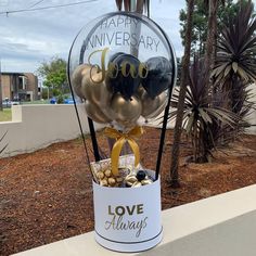 a vase filled with lots of balloons sitting on top of a sidewalk