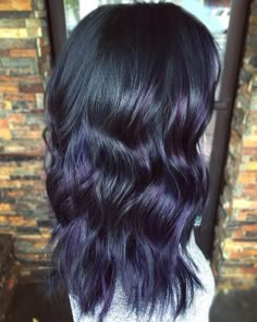 the back of a woman's head with long, wavy hair and purple highlights