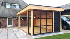 a small wooden building sitting in the middle of a yard next to a black van