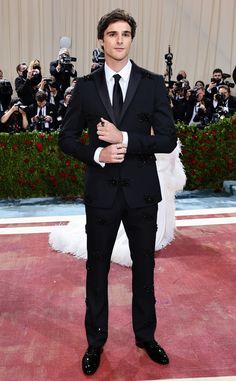 a man in a tuxedo standing on a red carpet