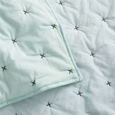 an unmade bed with green sheets and black stars on it's coverlet