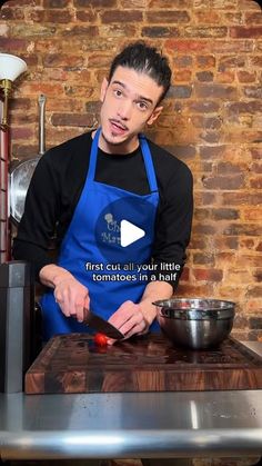 a man in an apron chopping tomatoes on a cutting board with a video screen