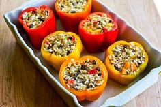 four stuffed peppers in a baking dish on a wooden table, ready to be eaten