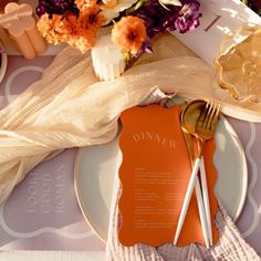 a place setting with orange and white plates, napkins and flowers on the table