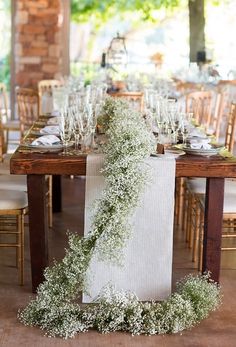 the table is set with white linens and greenery