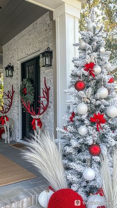 a decorated christmas tree in front of a house with red and white ornaments on it