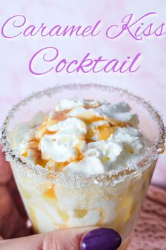 a hand holding a small glass filled with ice cream and caramel kiss cocktail on top of a table